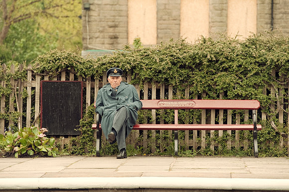 Uniformed man sat on a bench at Ramsdown (Ramsbottom) Steam Railway Station, part of the East Lancashire Railway